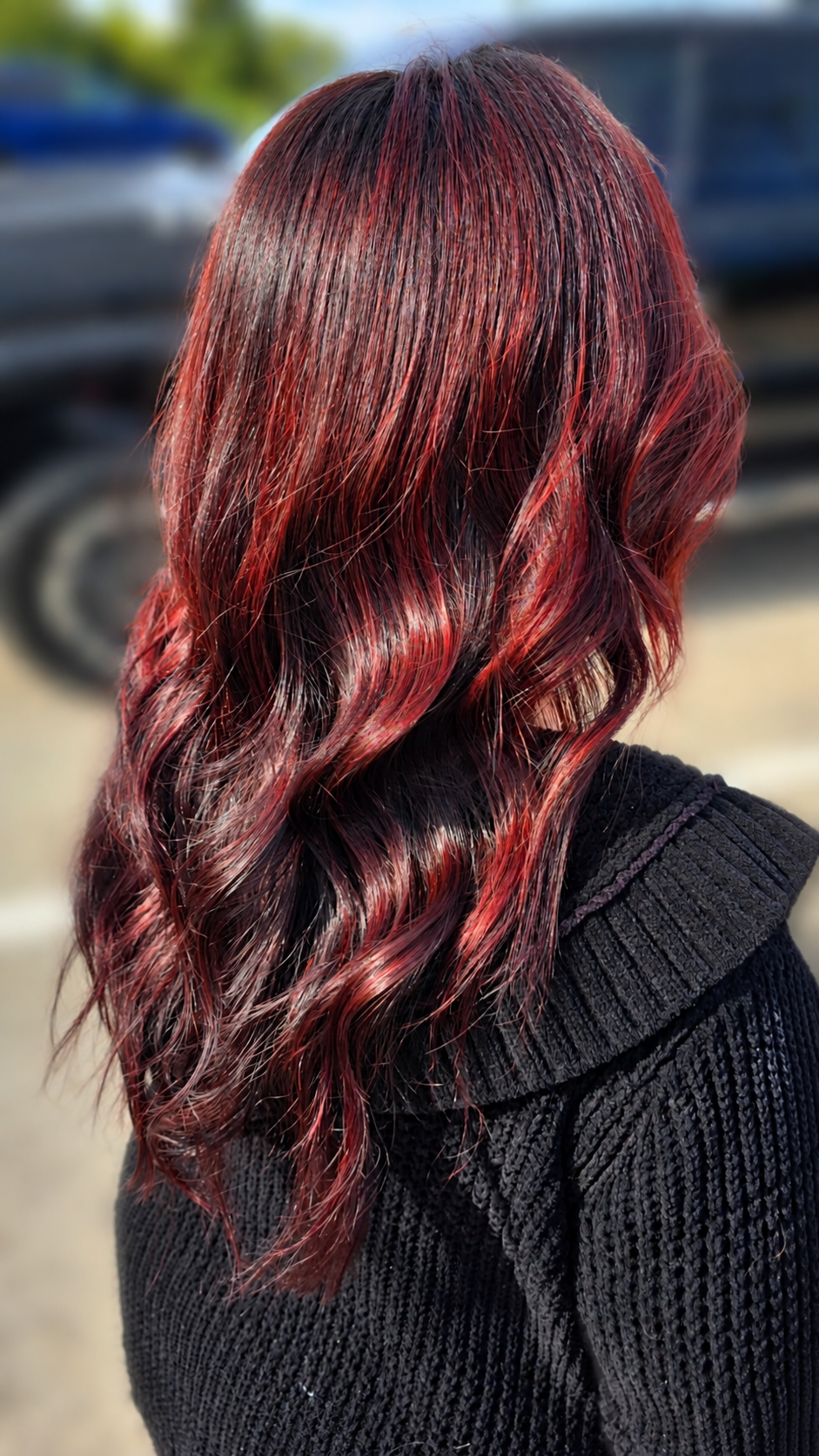 Dark hair with vivid red and burgundy highlights, wavy style