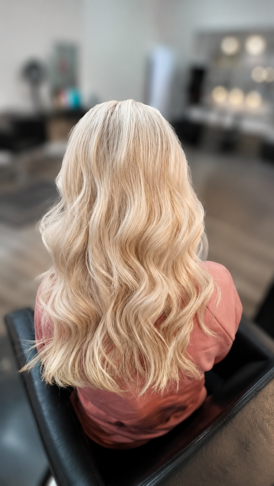 Long platinum blonde wavy hair from behind, salon setting