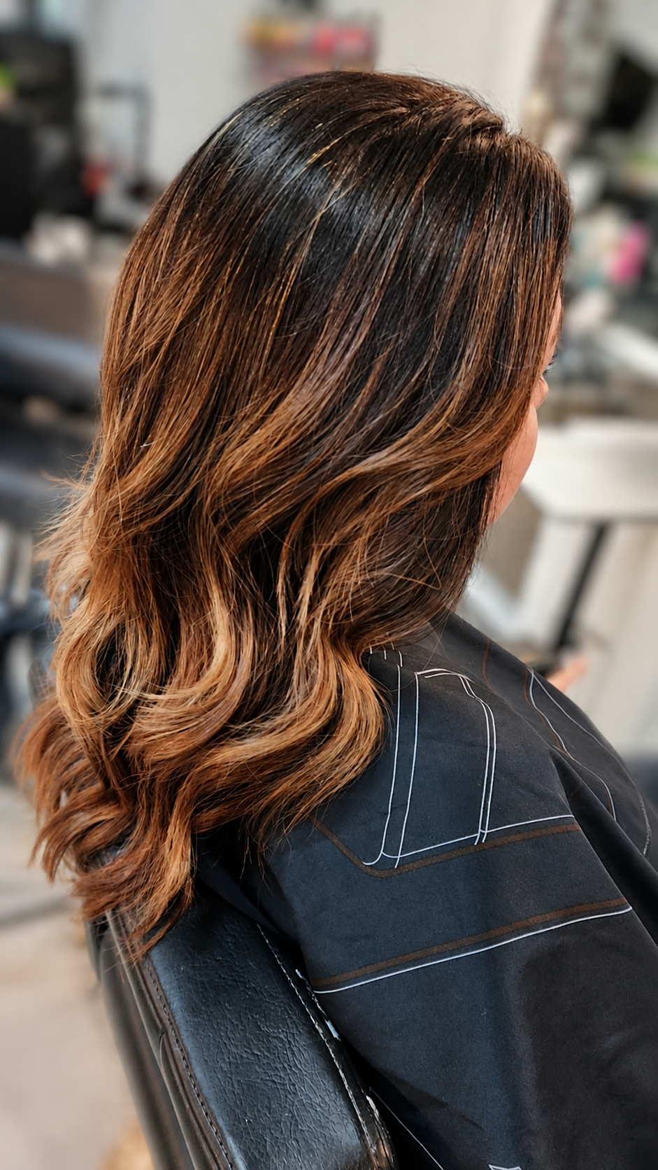 Dark brown hair with warm caramel balayage highlights, soft waves